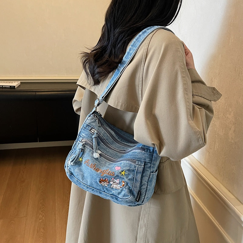 Denim Bloom Crossbody — worn or held by a model, supplier photograph